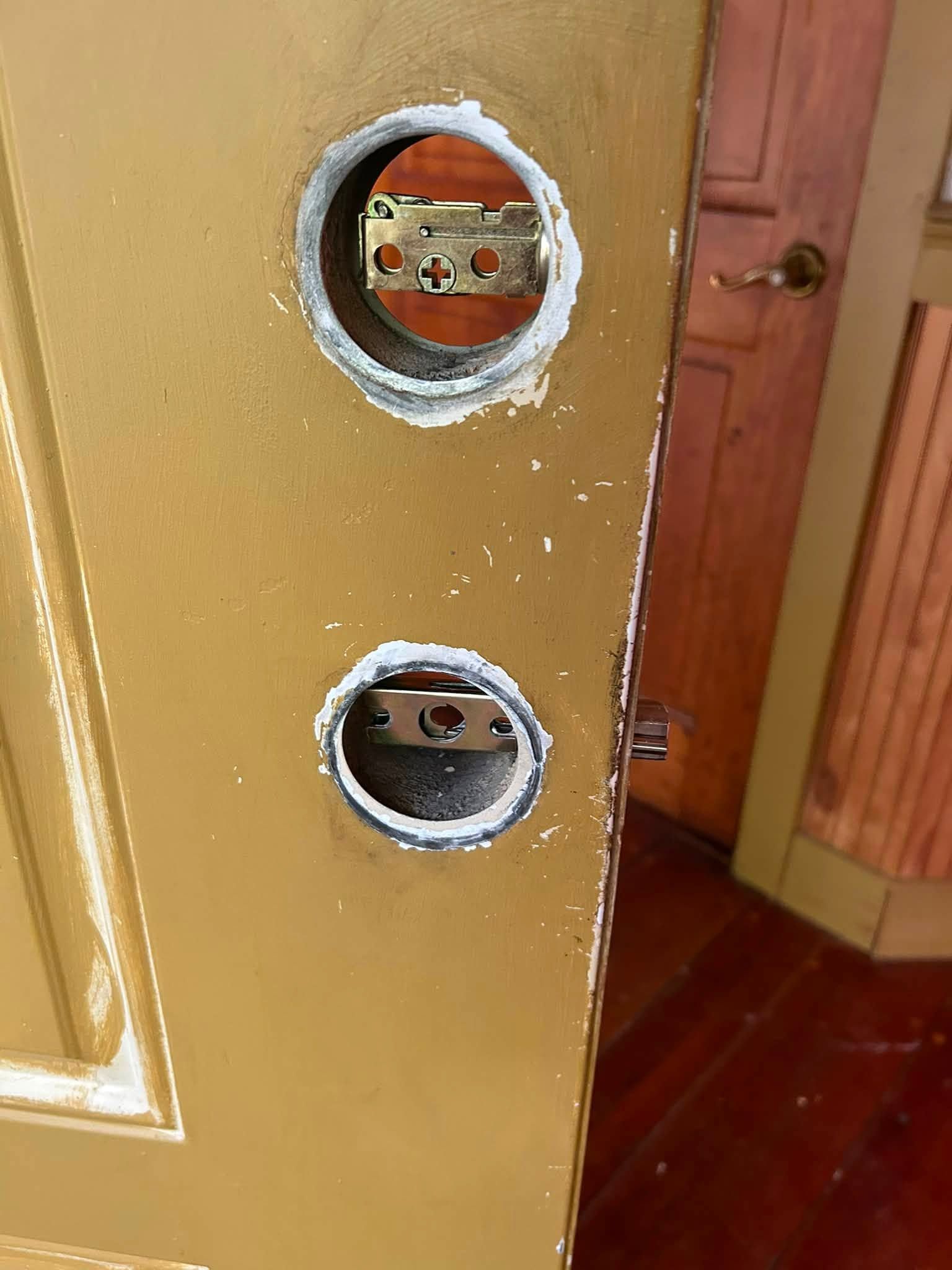Close-up of a gold door with two round holes where the lock hardware is missing