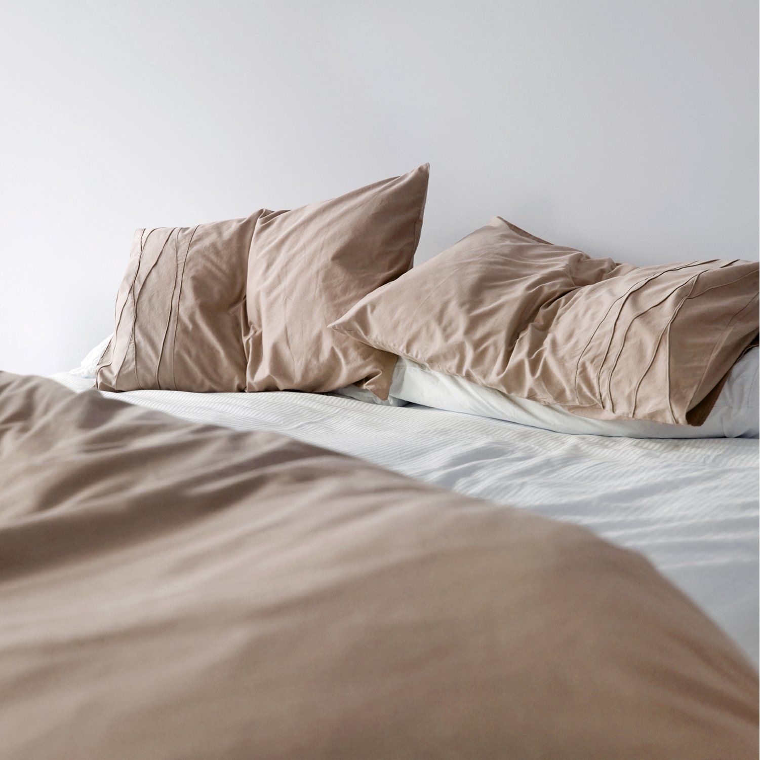 Folded beige bed sheet set.