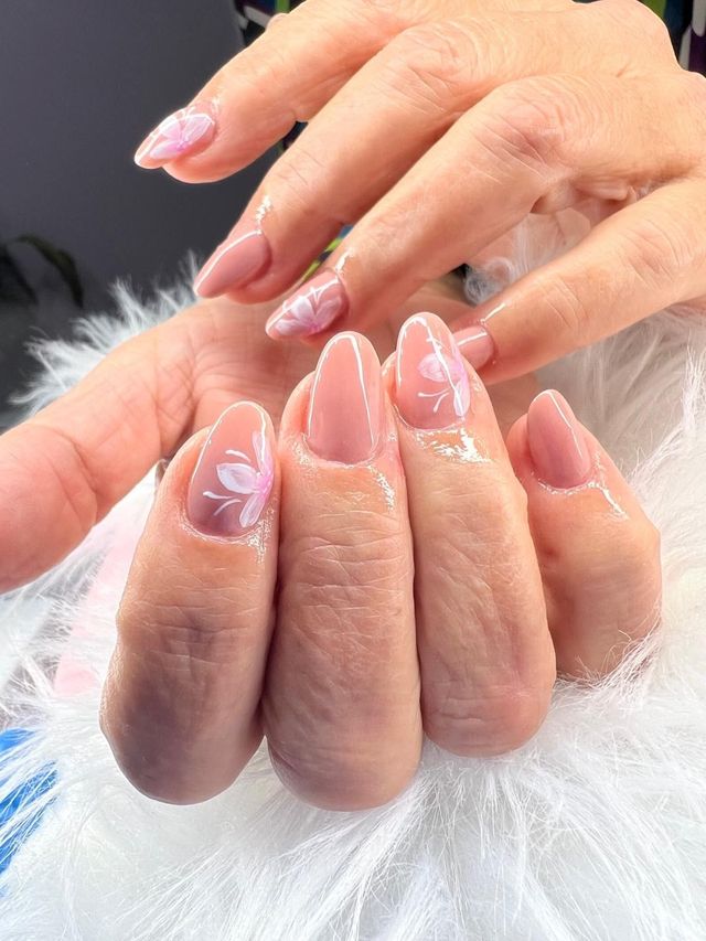Un primo piano delle unghie di una donna con un disegno floreale.