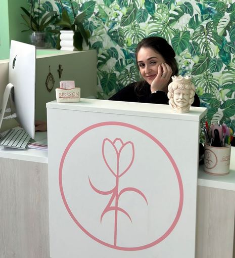 Una donna è seduta a una scrivania con un fiore rosa sopra