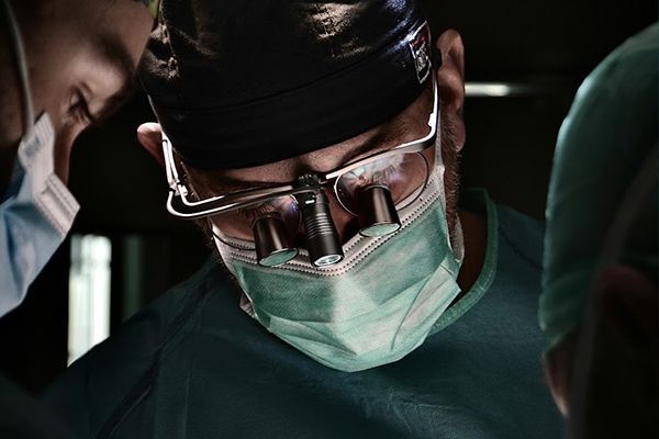 Surgeons in masks and goggles working under bright operating room lights