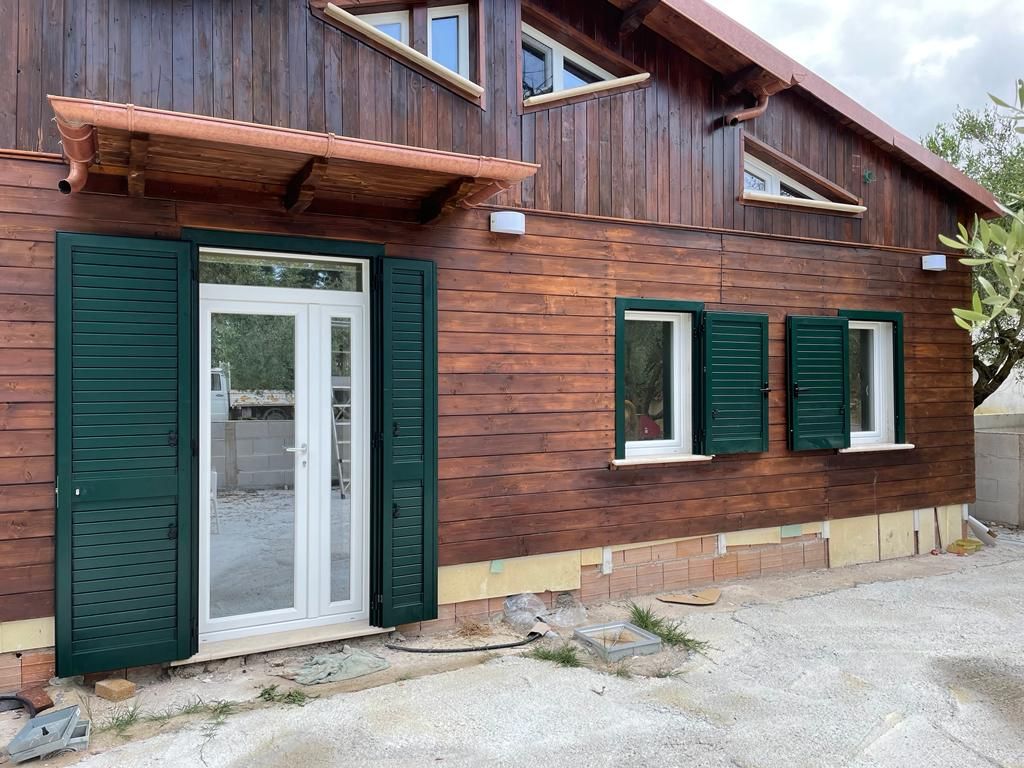 Edificio in legno con persiane verdi, porte e finestre bianche