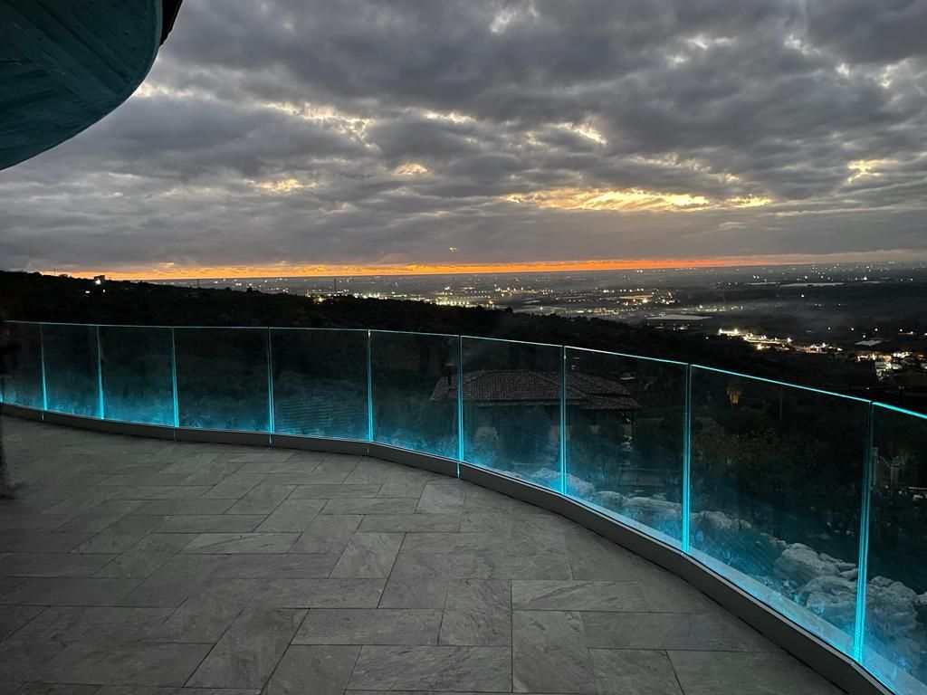 balcone in vetro con luci blu che si affaccia sulla città al tramonto