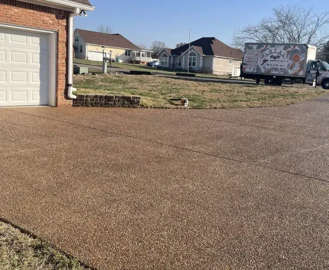 Suburban driveway and front yard with a moving truck parked near houses on a sunny day