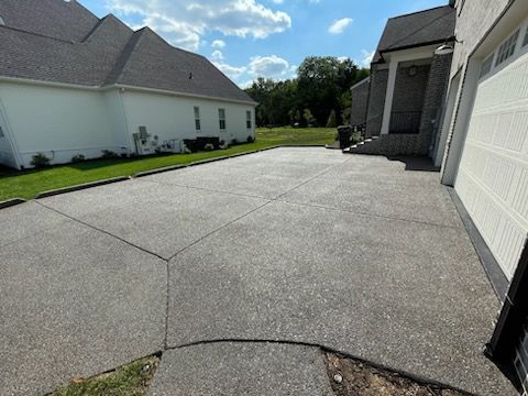 Concrete driveway beside white house and garage under a sunny blue sky