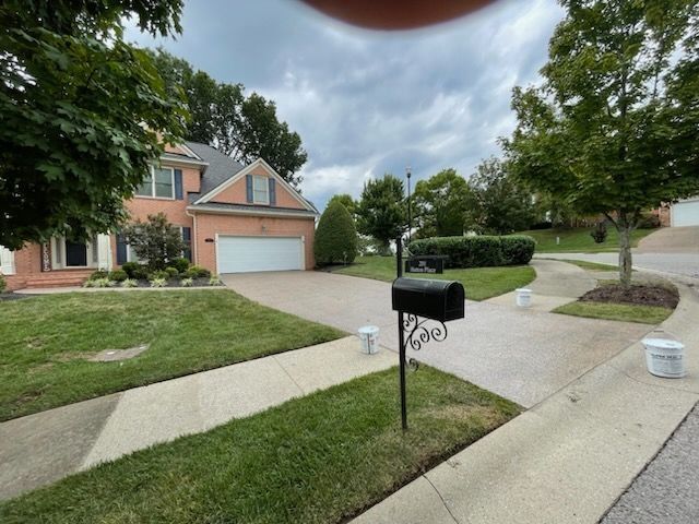 Suburban brick house with driveway, front lawn, and black mailbox by the curb