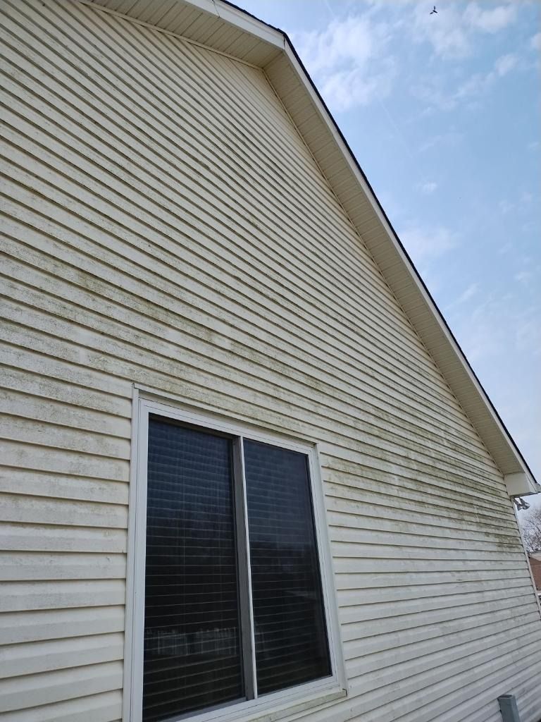 White-sided house exterior with a double window and sloped roof against a blue sky