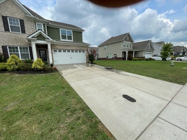 Suburban house with attached garage and wide concrete driveway under cloudy sky