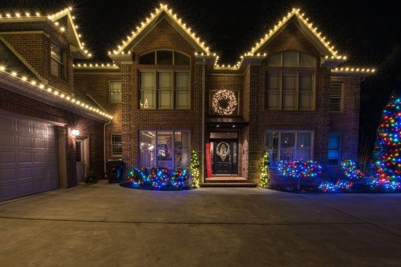 House decorated with warm white lights and blue holiday displays at night