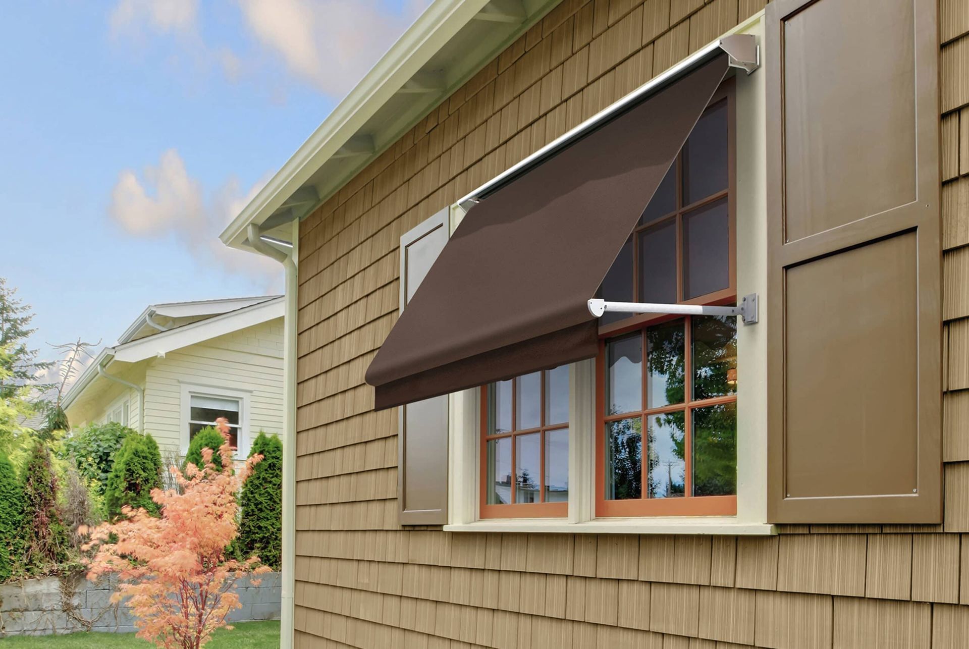 Brown window awning extended on a house with brown shutters and siding.