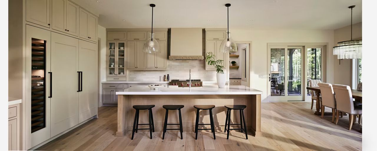 Modern kitchen with island, seating, cabinetry, and dining area with outdoor views.