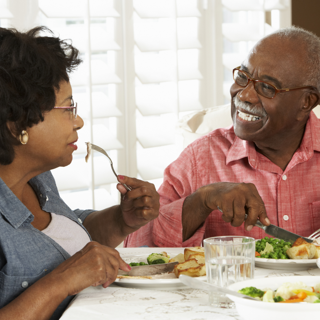 A man and a woman are sitting at a table eating food
