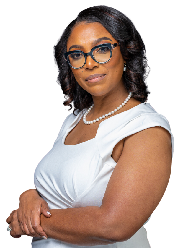 A woman wearing glasses and a pearl necklace is standing with her arms crossed.