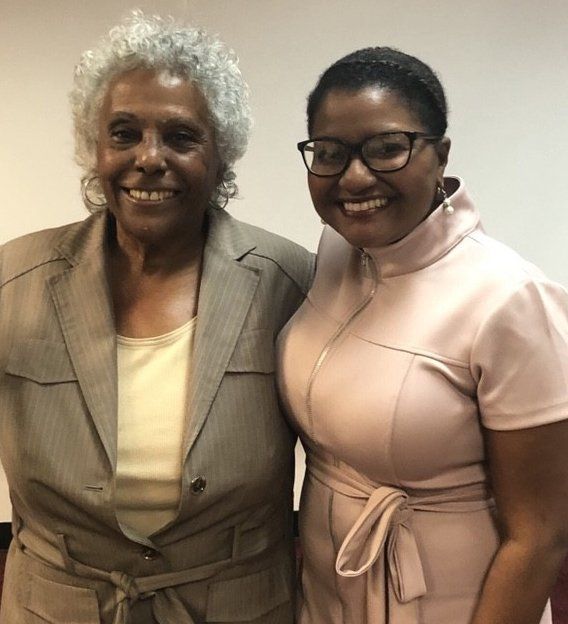 Two women are posing for a picture and one is wearing glasses