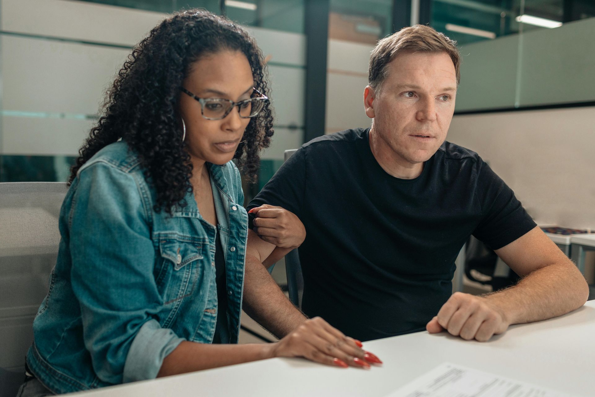 A man and a woman are sitting on a couch signing a document.