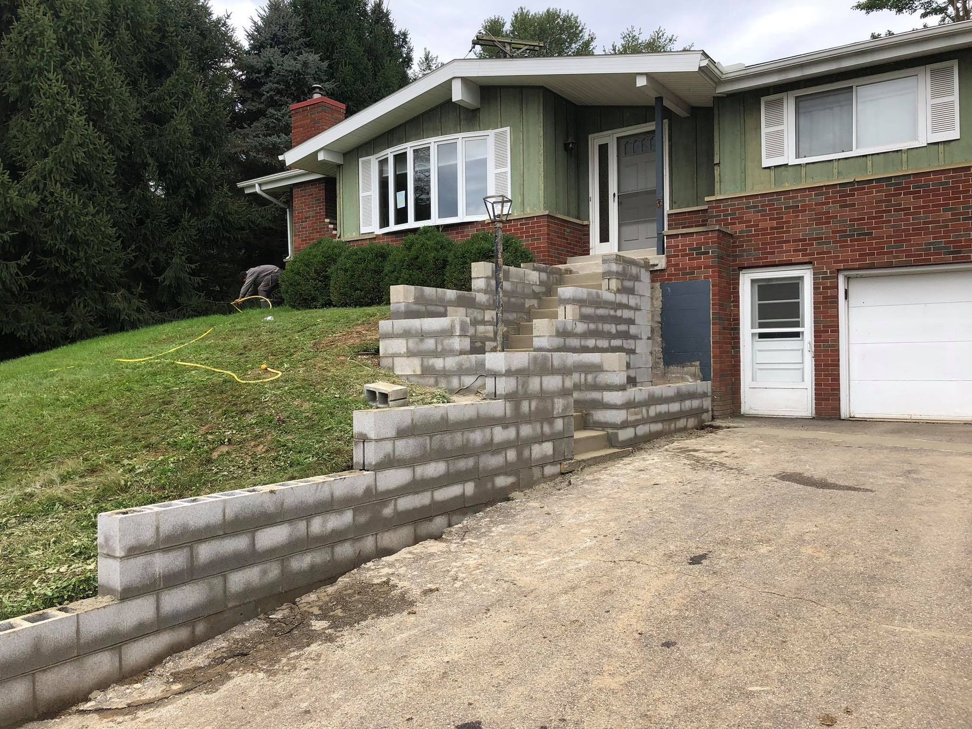 A house with a brick wall and stairs in front of it.