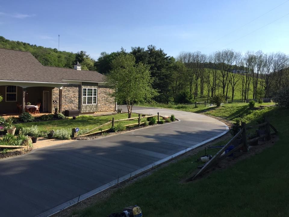 A house with a driveway leading to it is surrounded by grass and trees.