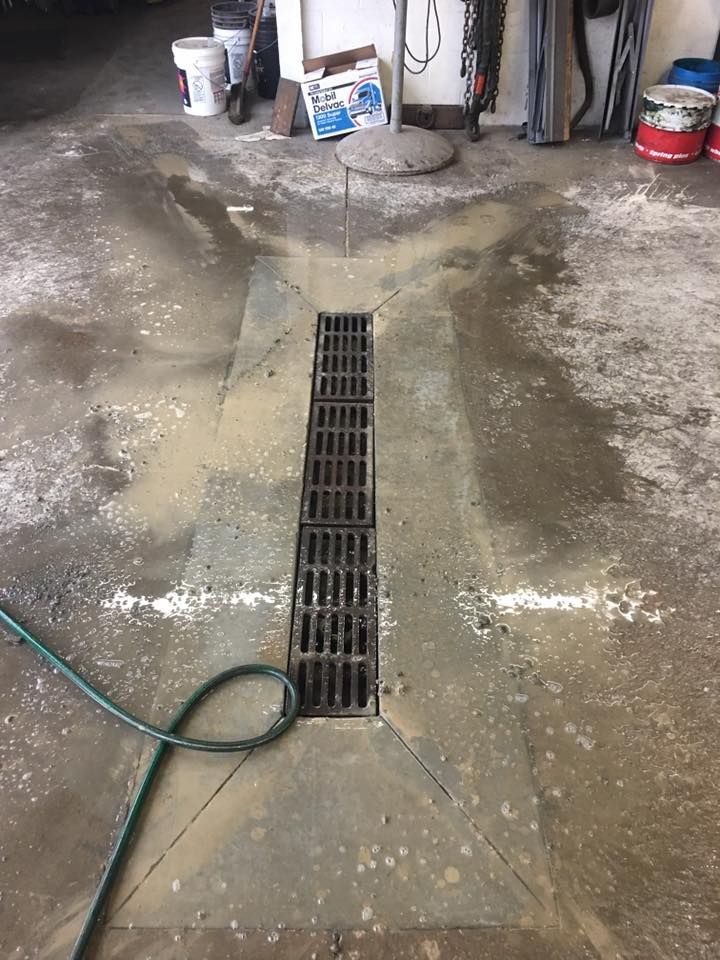 A drain in a garage with a hose attached to it.