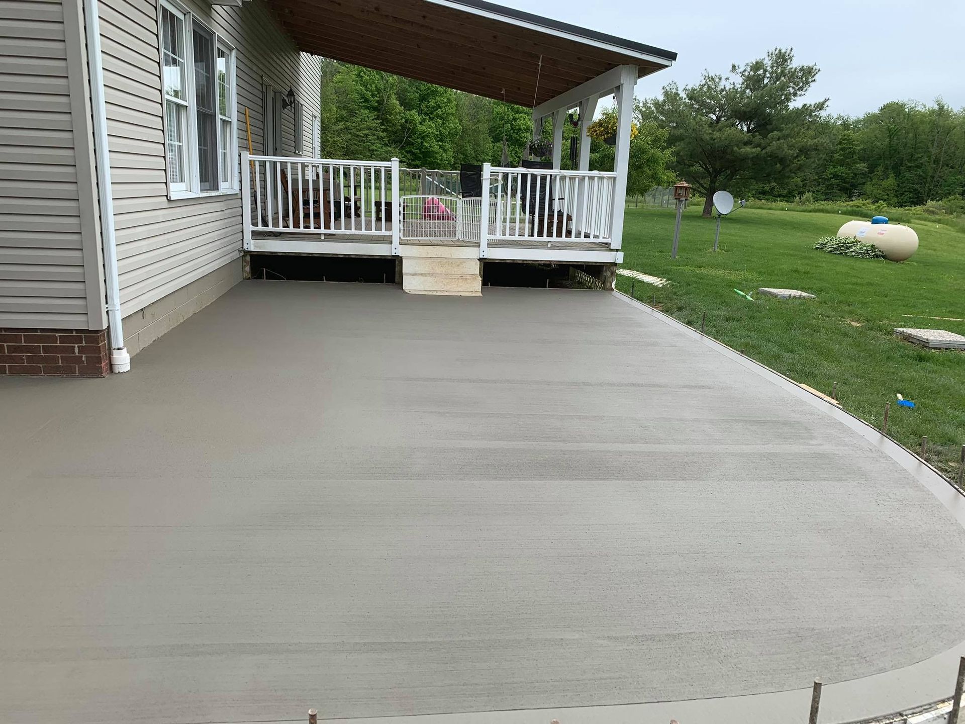 A concrete porch is being built in front of a house.