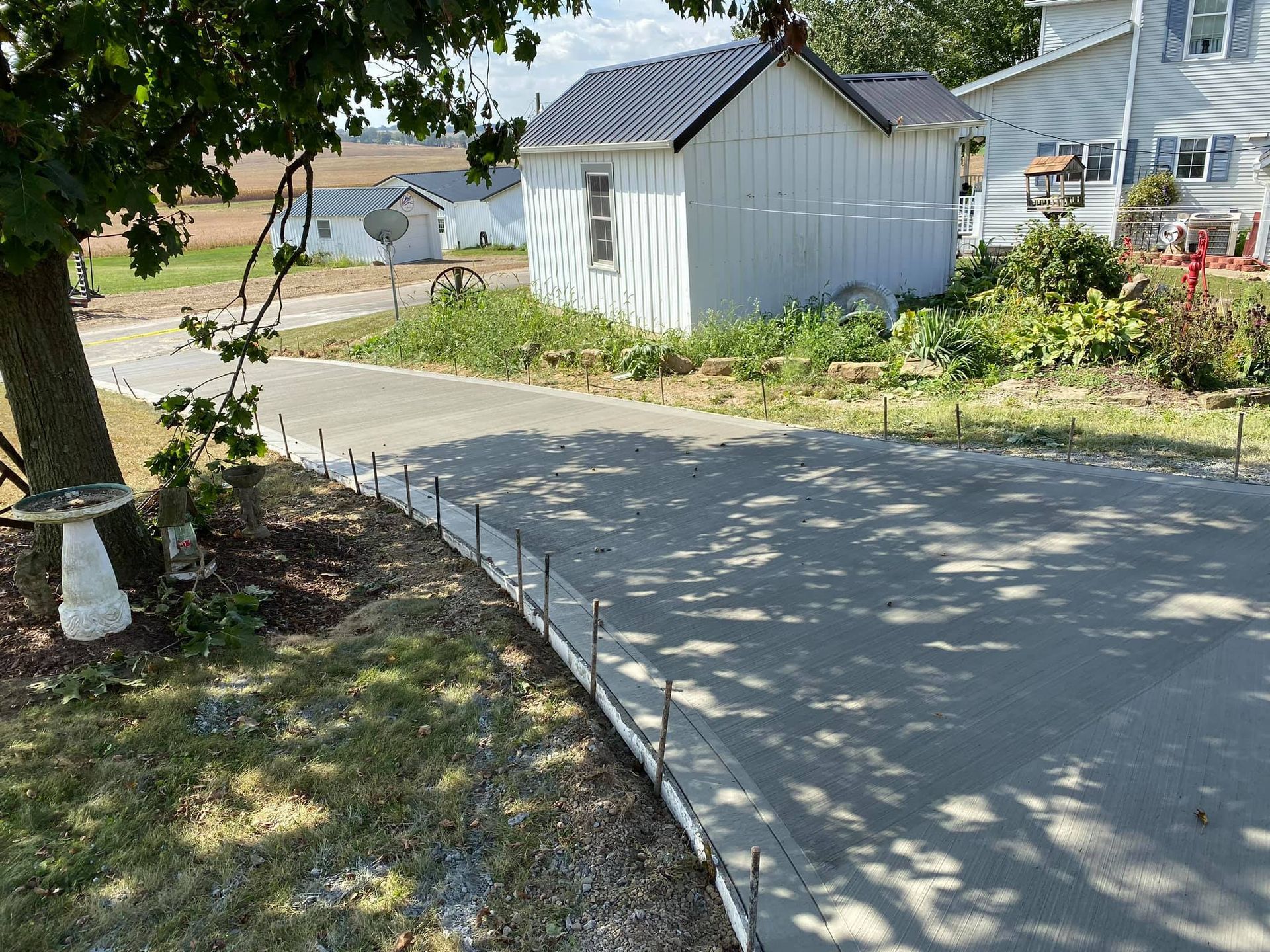 A concrete driveway is being built in front of a white house.
