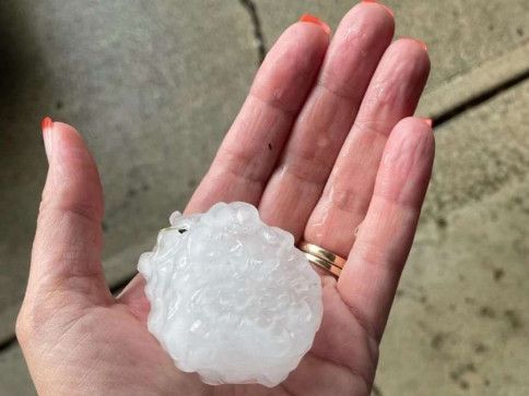 A person is holding a piece of hail in their hand.