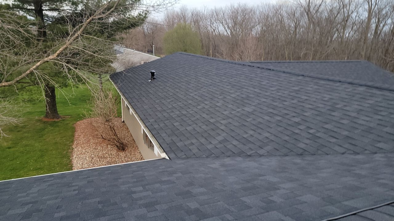 A house with a black roof and trees in the background.