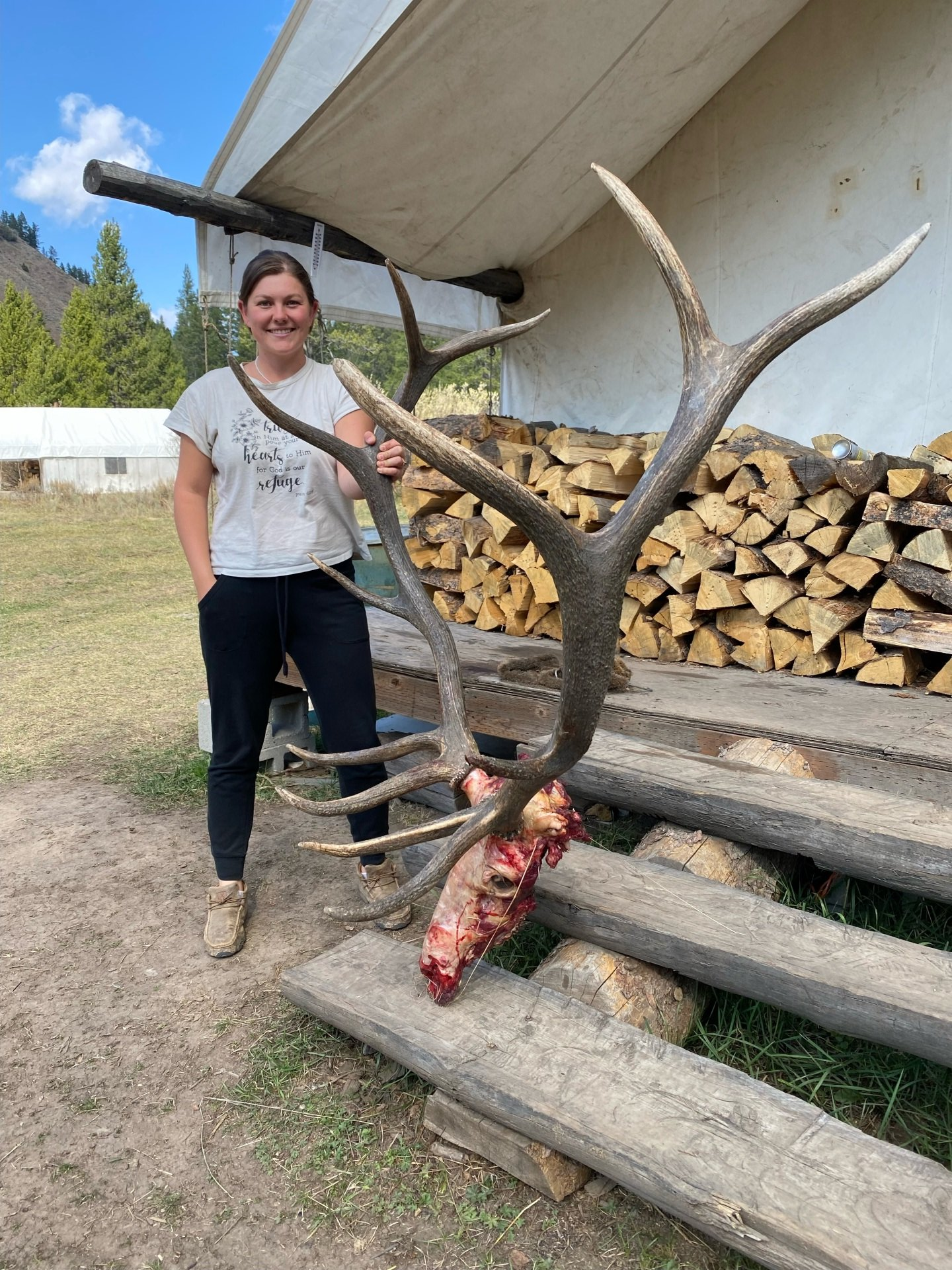A woman is standing next to a large deer antlers.