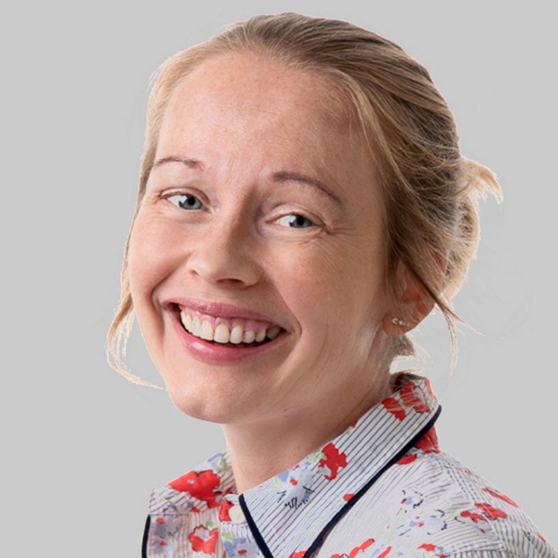 Smiling woman with blonde hair in a bun, wearing a floral shirt.