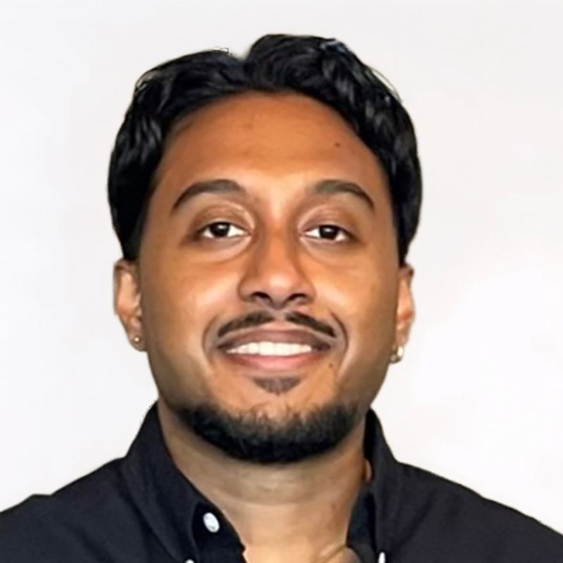 Smiling man with dark hair and goatee, wearing a black button-down shirt.
