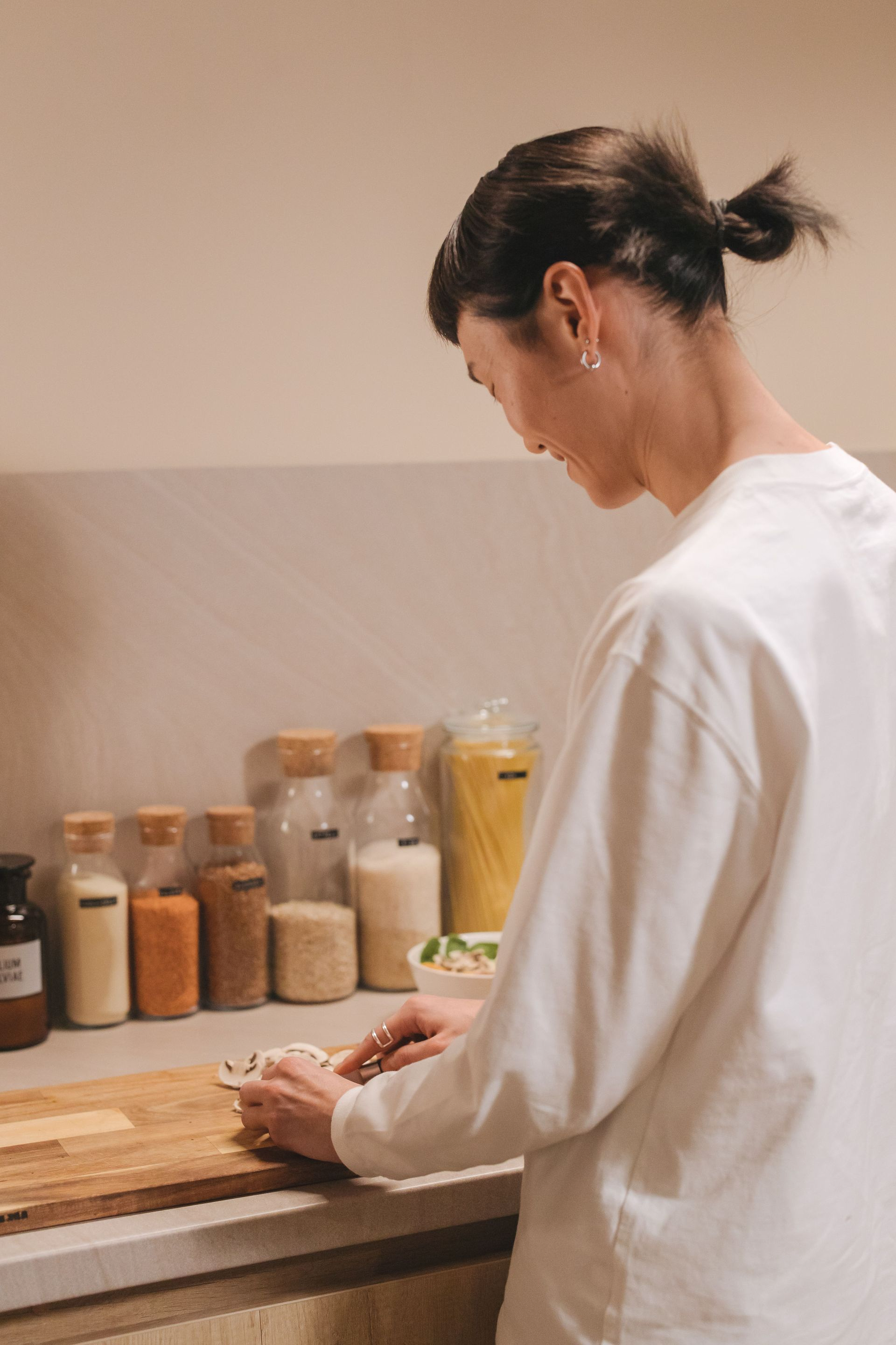 Person in a white shirt preparing food at a kitchen counter with jars of ingredients.