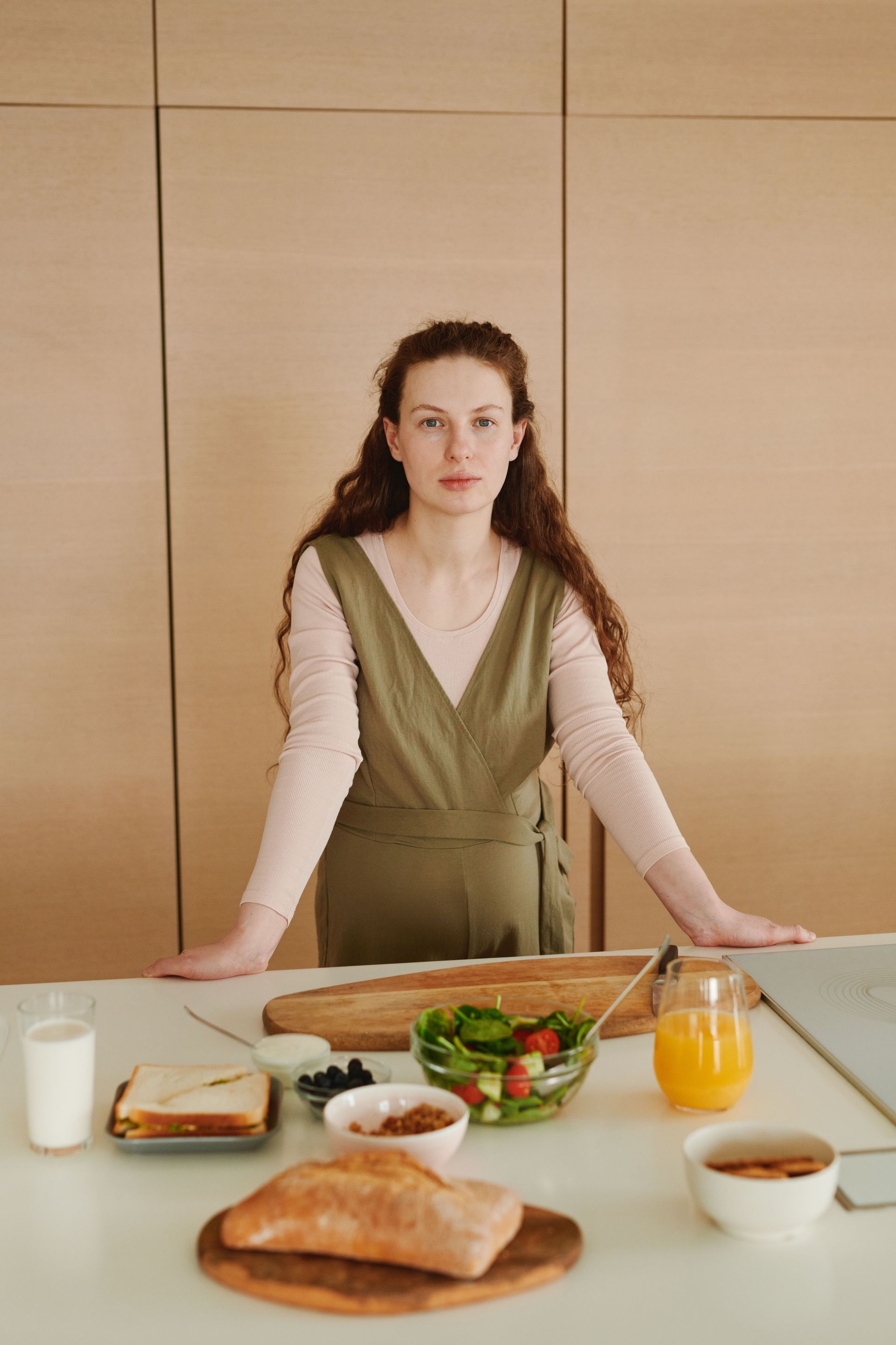 Person standing behind a table with breakfast foods and orange juice in a bright room