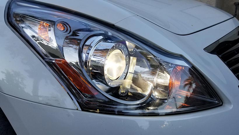 Close-up of a silver car’s headlight with chrome details and amber turn signal casing