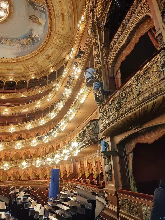 Interior ornamentado del teatro con balcones dorados, candelabros y butacas en el escenario bajo una cúpula decorada.