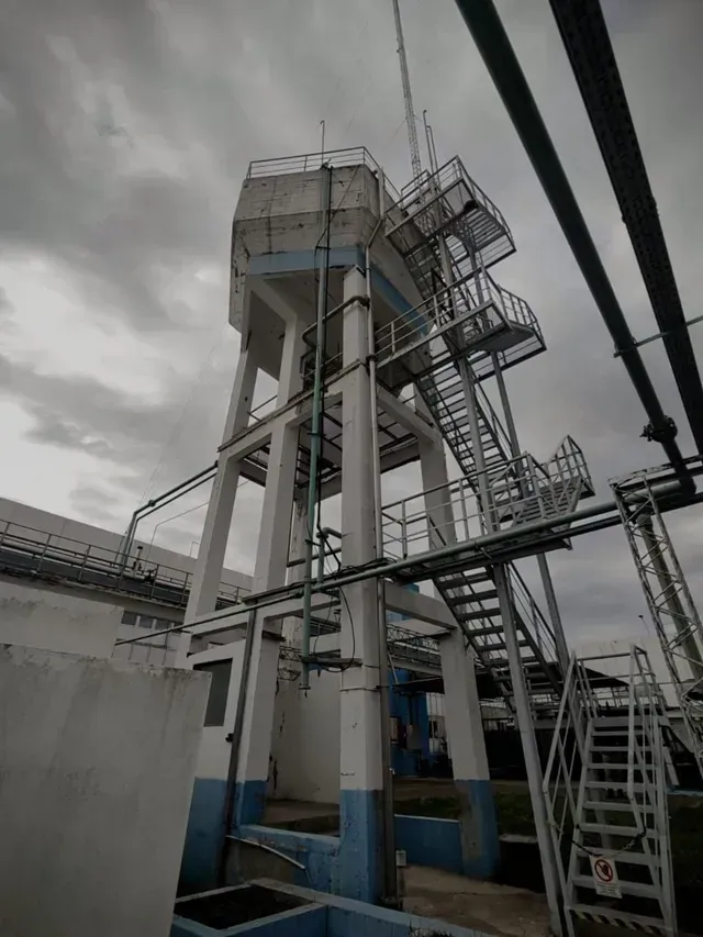 Torre de escaleras y plataforma de metal de estilo industrial contra un cielo nublado.