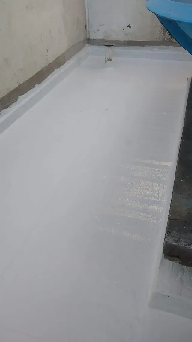 Pasarela o suelo revestido de blanco junto a una pared, con un objeto azul en la esquina y un borde oscuro a la derecha.