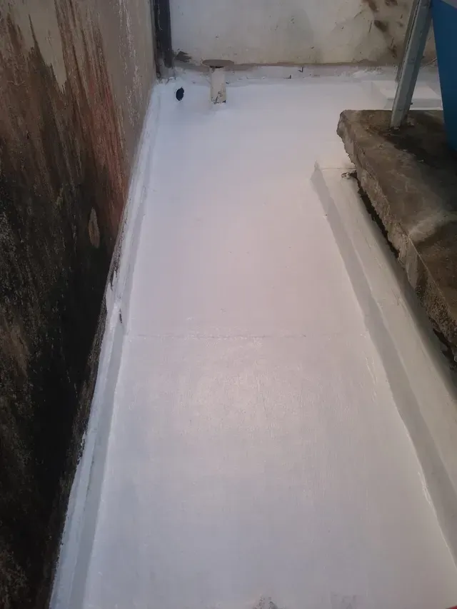 Suelo blanco recién pintado en un estrecho pasillo exterior junto a una pared y escalones.