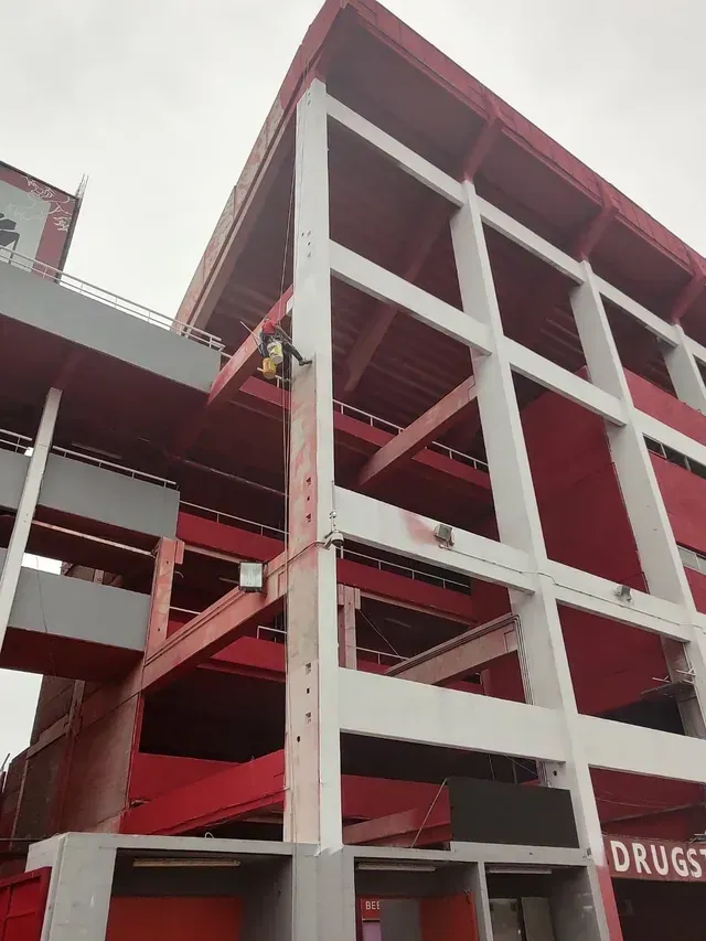 Edificio rojo de varias plantas con estructura de hormigón visto y hueco de escalera, visto desde abajo.