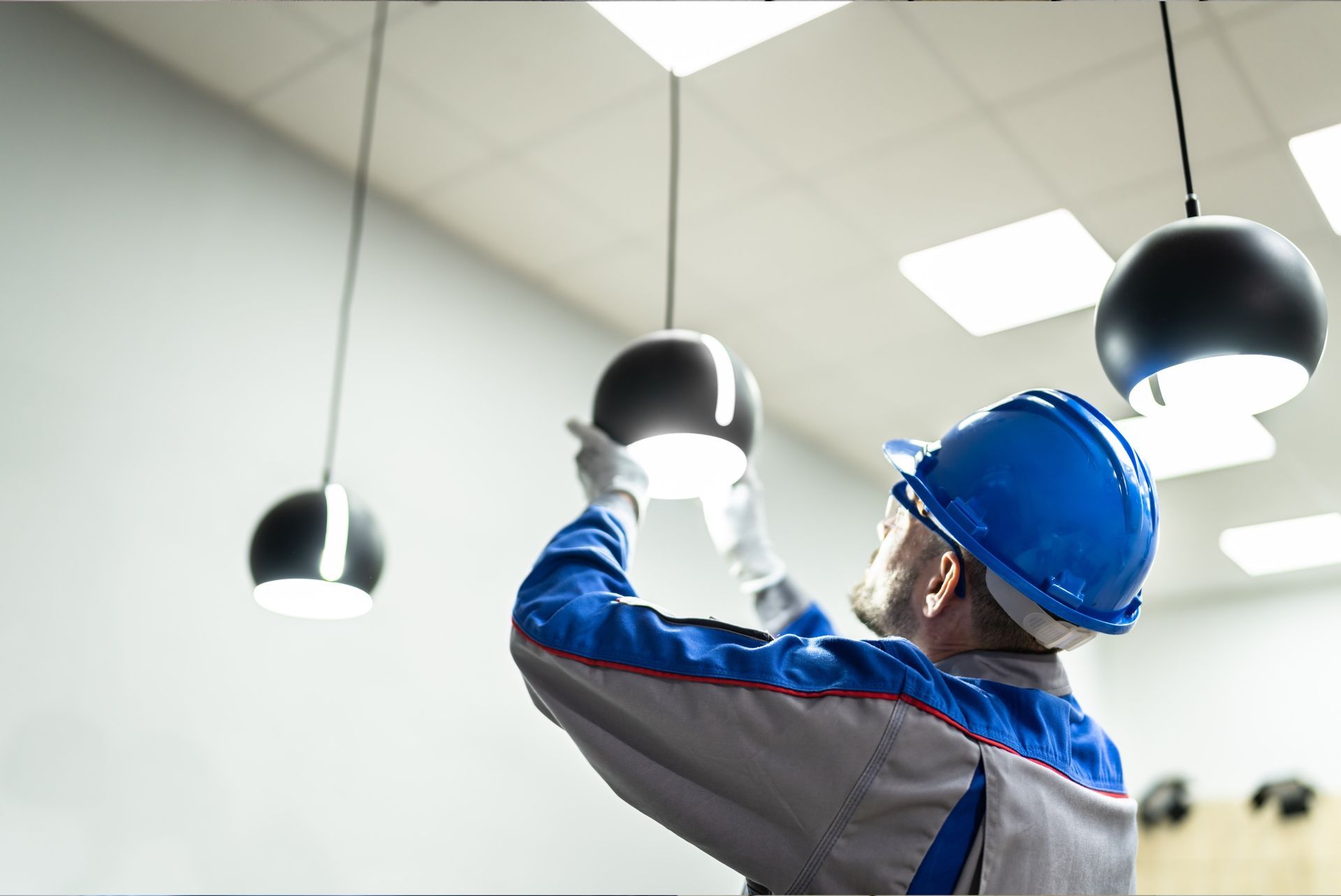 a man in a hard hat is installing a light fixture .