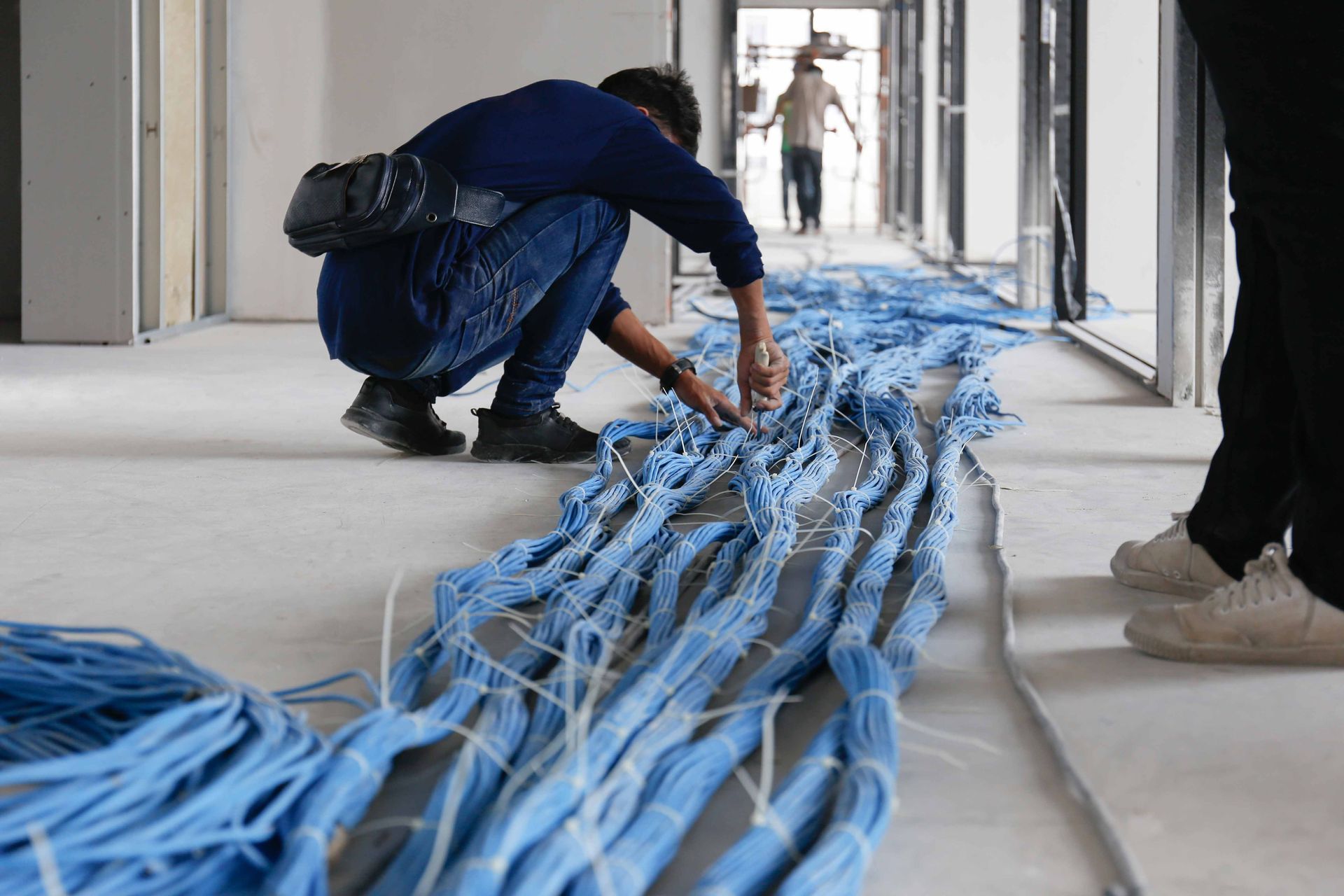 a man is working on a bunch of blue wires on the floor .