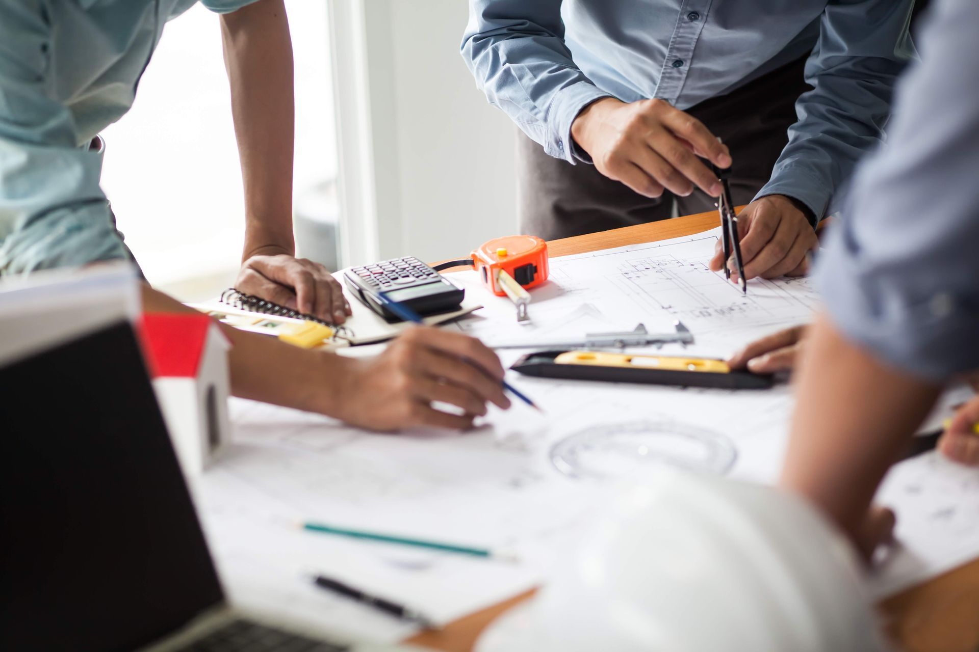 a group of people are sitting around a table looking at a blueprint .