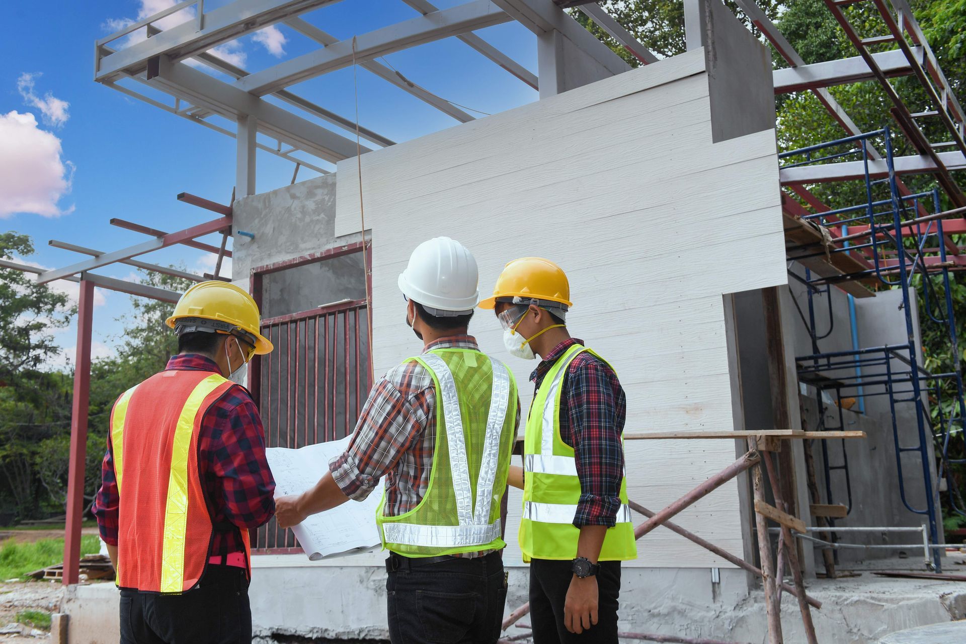 a group of construction workers are looking at a blueprint at a construction site .