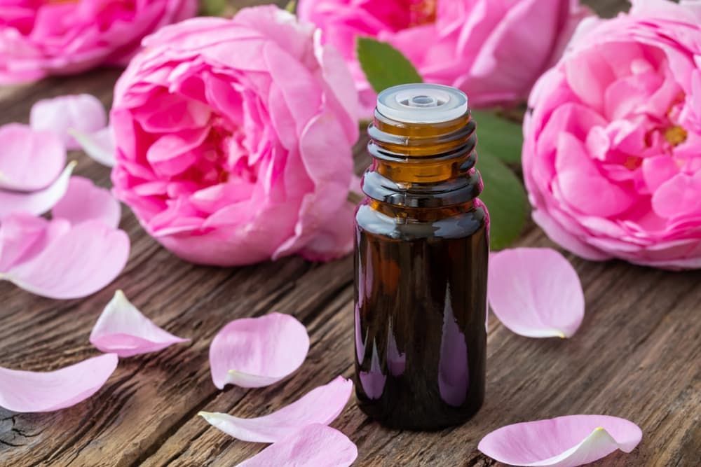A Bottle of Essential Oil Is Surrounded by Pink Flowers — Crystal Cauldron in South Mackay, QLD