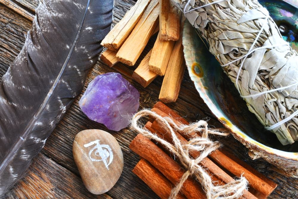 A Wooden Table Topped with Feathers , Sage and A Rock — Crystal Cauldron in South Mackay, QLD
