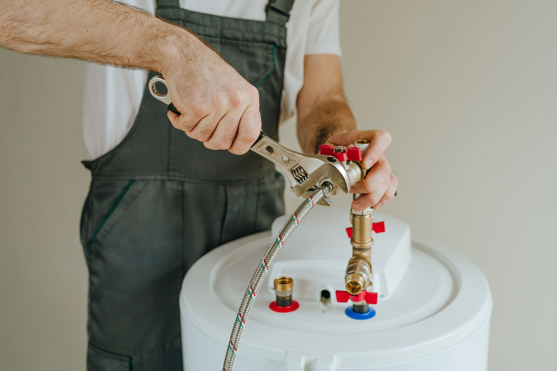Technician repairing water heater connection with wrench adjustment.