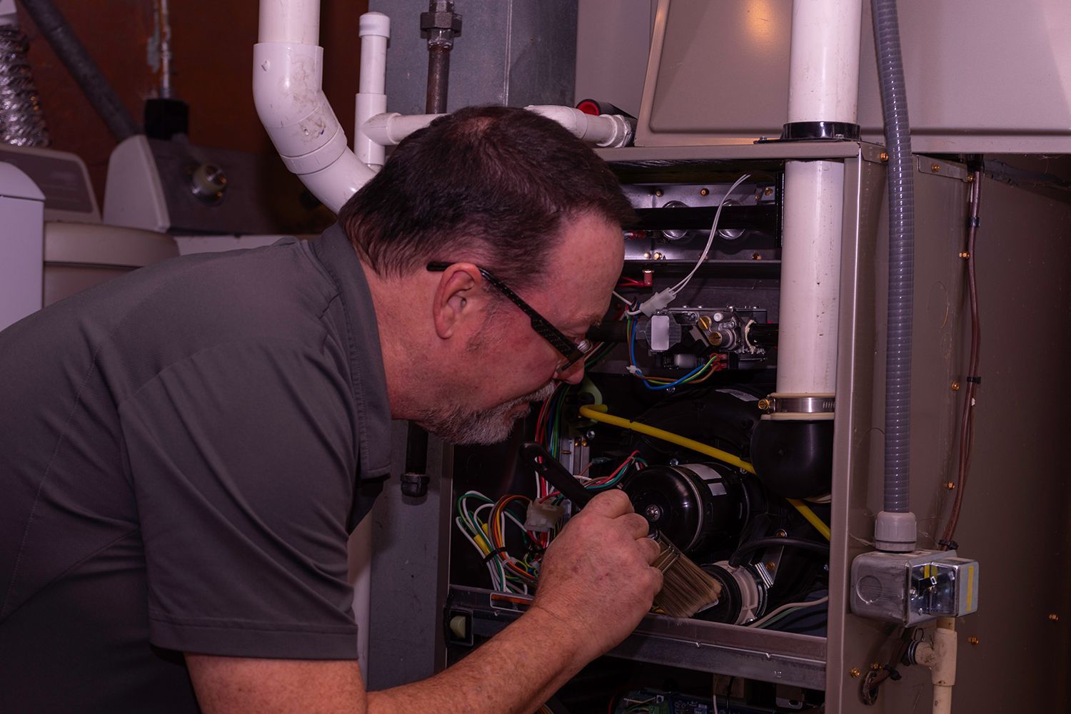 Worker examining components inside a furnace during a repair service. Worker examining components inside a furnace during a repair service.