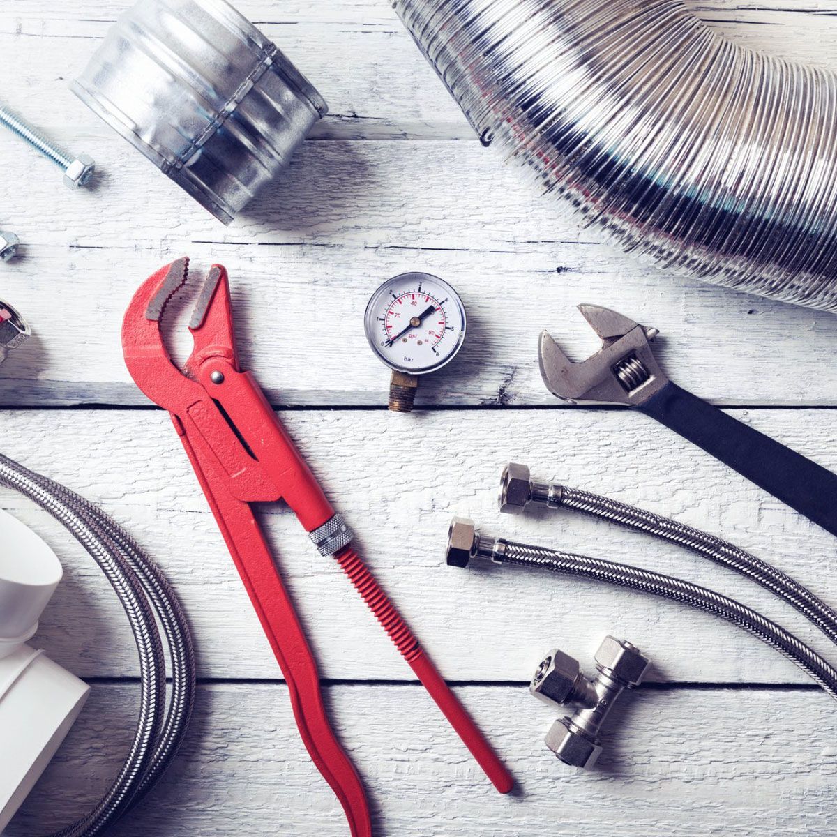 A bunch of plumbing tools are on a wooden table. A bunch of plumbing tools are on a wooden table.