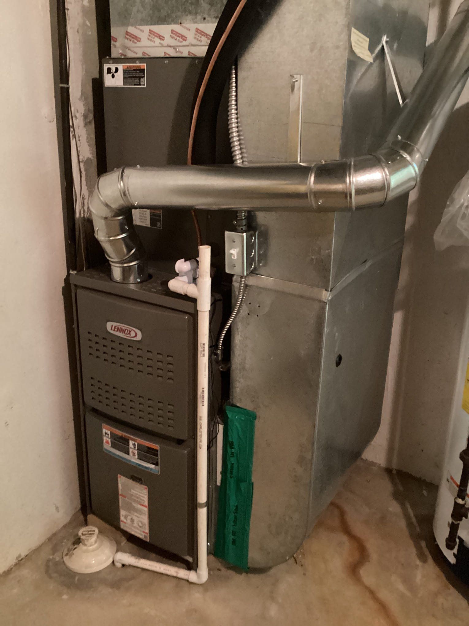 A furnace is sitting in a basement next to a water heater.