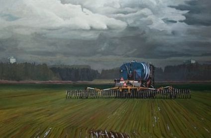 Een tractor die een grote strooier voor vloeibare kunstmest over een veld trekt onder een dramatische, donkere hemel.