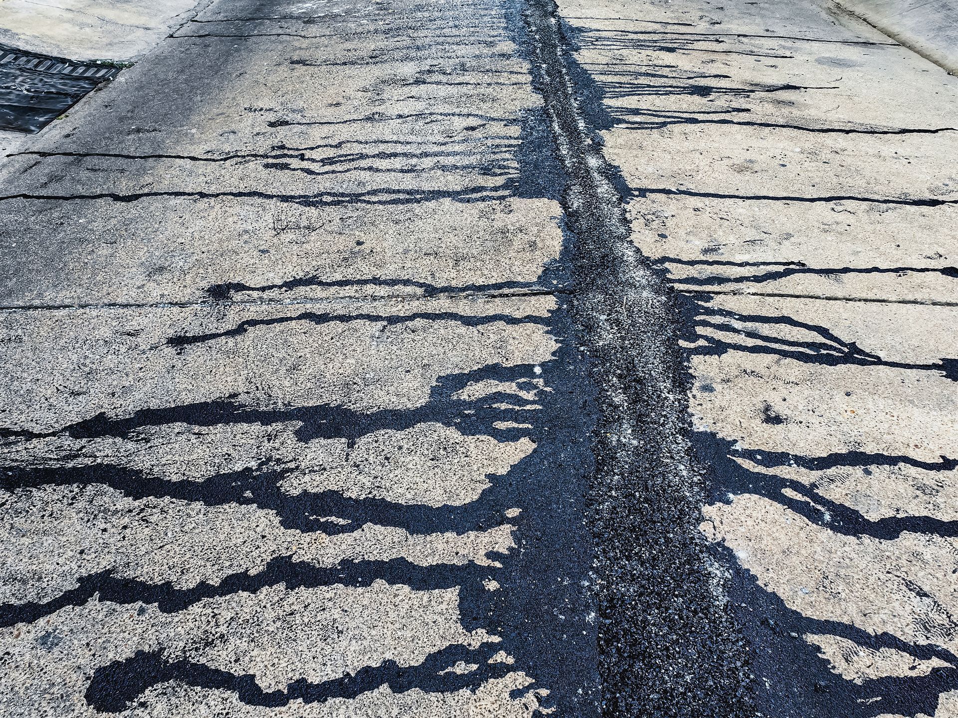 Cracked asphalt road with a long dark repair seam running down the center Cracked asphalt road with a long dark repair seam running down the center