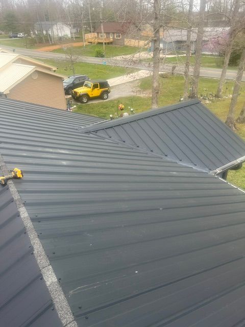 View from a rooftop over a neighborhood street with a yellow vehicle and bare trees on a cloudy day